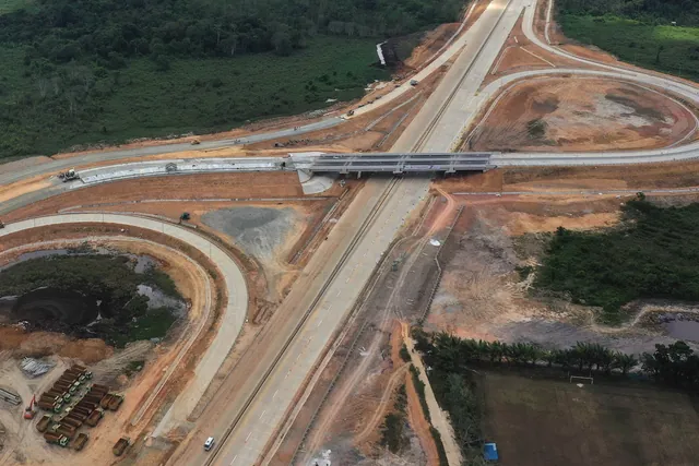 Foto udara jalan tol baru dengan simpang susun di tengah hutan