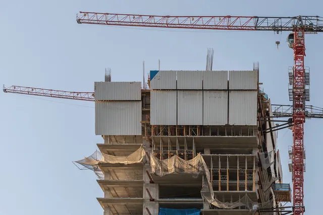 Puncak gedung beton yang sedang dibangun dengan kren menara merah