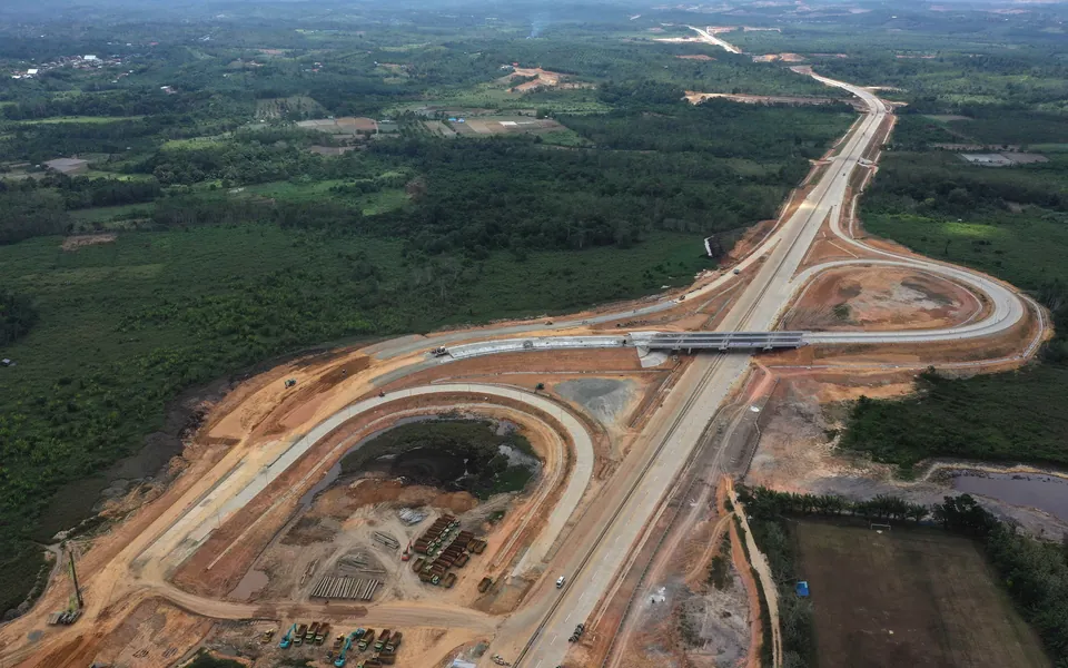 Foto udara jalan tol baru yang sedang dibangun dengan simpang susun di antara hutan